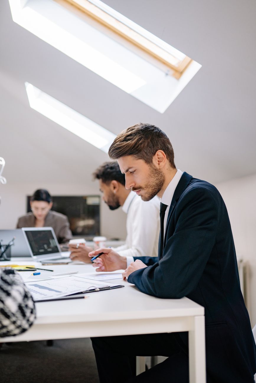 a side view of a man in black suit working inside the office